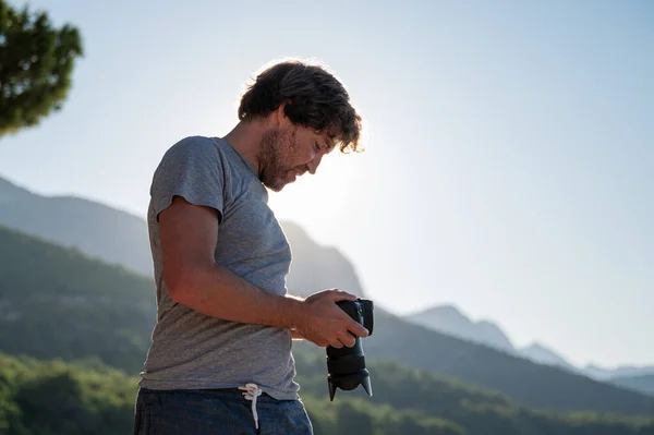若い男性の写真家は 美しい夏の朝に外に立って 彼のDslrカメラの表示の設定をチェック — ストック写真