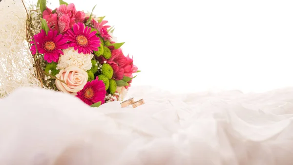 两个结婚戒指 旁边是一束美丽的艳丽的花束 点缀着柔和的米色面料 — 图库照片