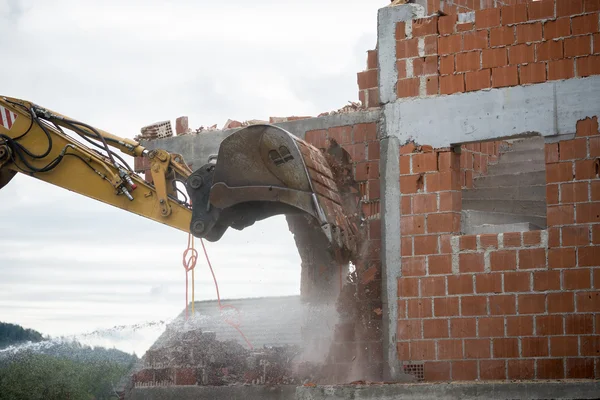 Backhoe demolir uma casa de tijolos — Fotografia de Stock