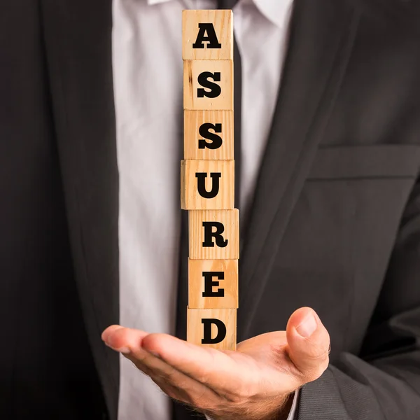 Businessman Holding Letter Blocks Spelling Assured — Stock Photo, Image