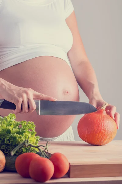 Pregnant woman slicing fresh vegetables — Stock Photo, Image