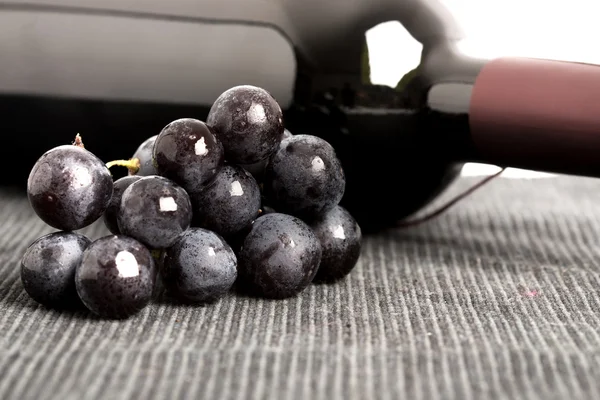Black grapes and a bottle of red wine — Stock Photo, Image