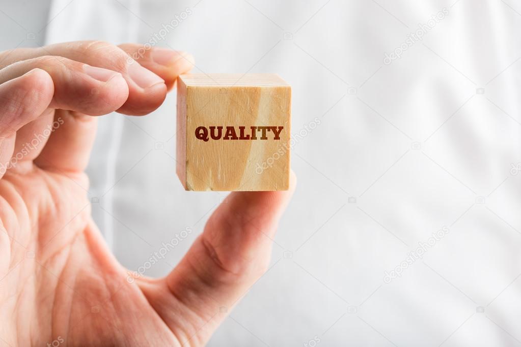 Man holding a wooden block reading - Quality