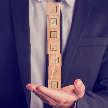 Businessman holding a stack of checked boxes clipart