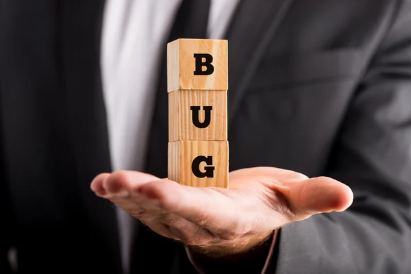 Zakenman die houdt van houten blokken met het woord Bug — Stockfoto