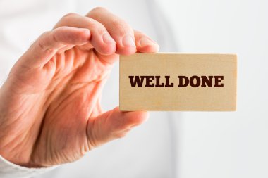 Küçük tutan adam Aferin metnini gösteren ahşap parça