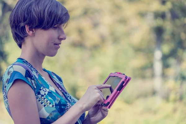 ピンクのタブレットを屋外で使う若い女性 — ストック写真