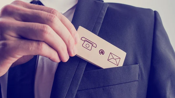 Man removing a card with contact icons from the pocket of his ja — Stock Photo, Image