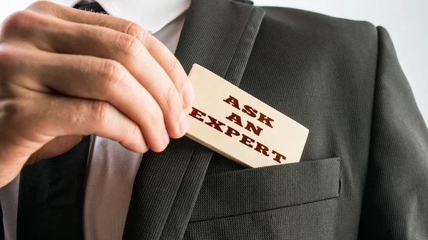 Empresário mostrando uma leitura de cartão de madeira Pergunte a um especialista — Fotografia de Stock
