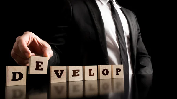 Businessman Arranging Small Wooden Pieces with Develop Letters — Stock Photo, Image