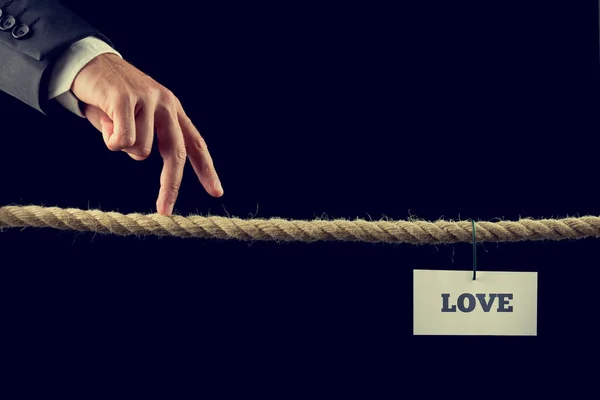Man walking his fingers along a length of rope towards Love — Stock Photo, Image
