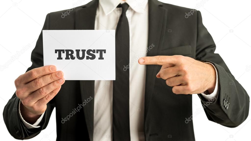 Business man holding a white card saying Trust