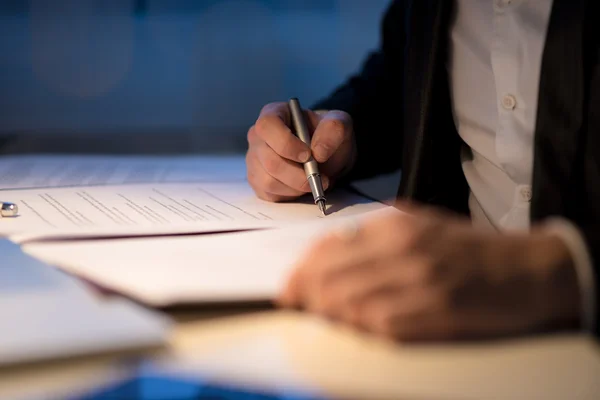 Бизнесмен, работающий допоздна, подписывая документ или контракт — стоковое фото