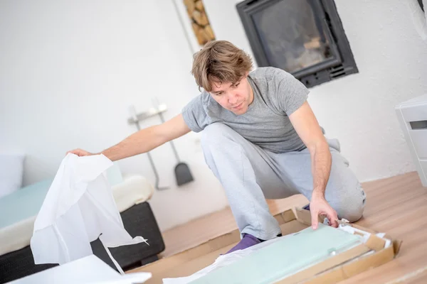 Man uitpakken van een pakket op de verdieping — Stockfoto