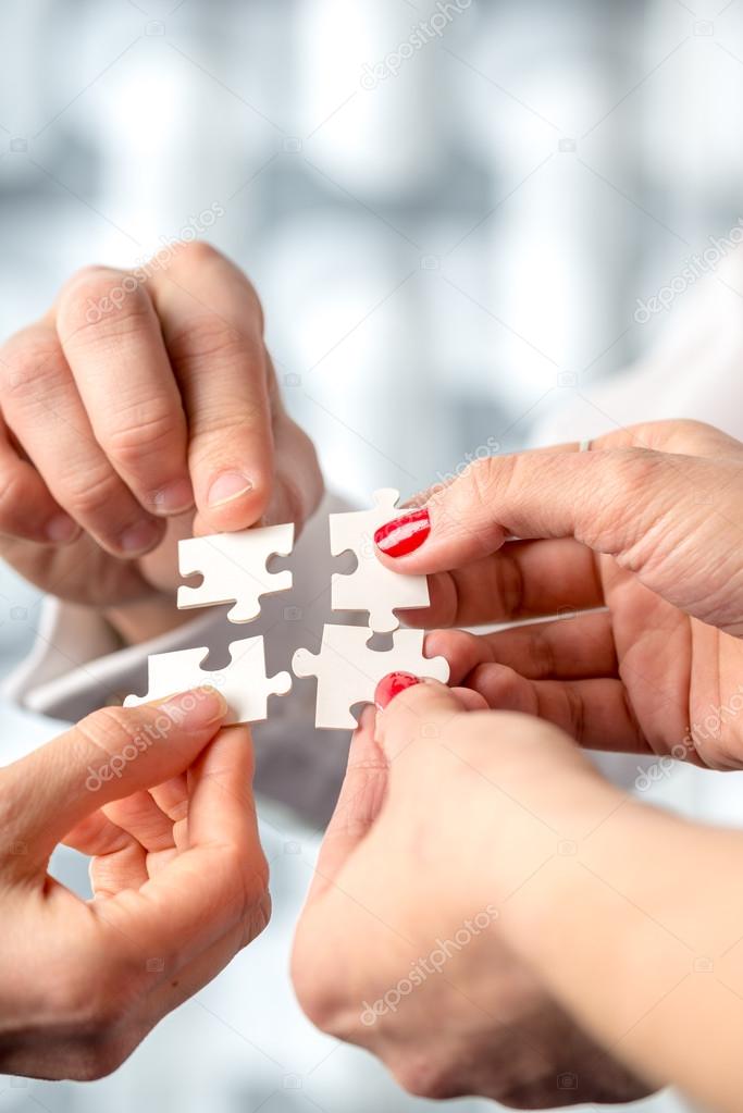 Four hands fitting together matching interlocking puzzle pieces — Stock