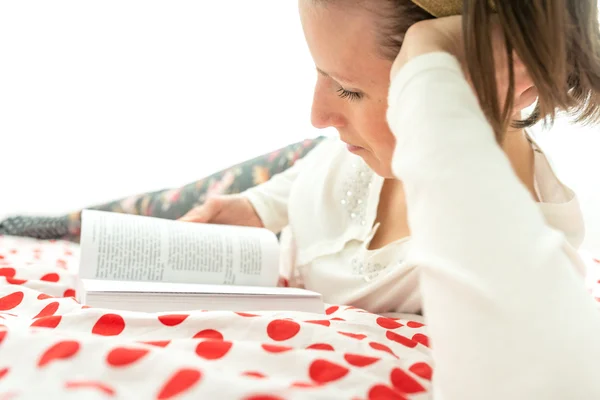 Mladá žena uvolňující na posteli s knihou — Stock fotografie