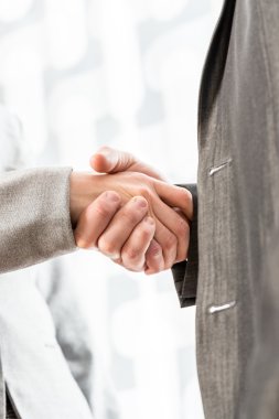 Bulanık bir arka plan üzerinde el sıkışan iş adamları