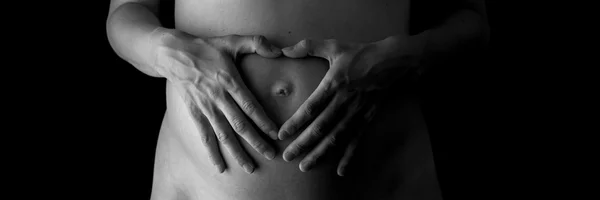 Mãos de mulher fazendo forma de coração em sua barriga grávida — Fotografia de Stock