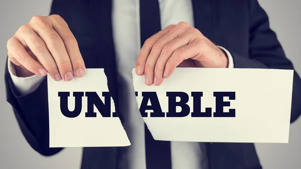 Man holding a torn paper sign in his hands with the words - Un - — Stock Photo, Image