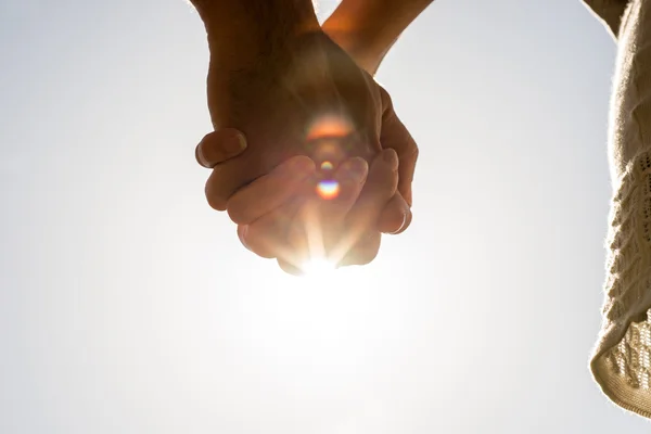 Clasped hands against a bright sun flare — Stock Photo, Image