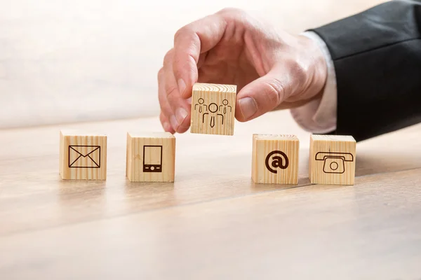 Man Arranging Wooden Cubes with Contact Symbols Royalty Free Stock Images