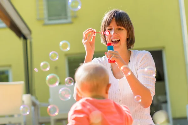 Happy mother blowing bubbles for his baby — Stok Foto