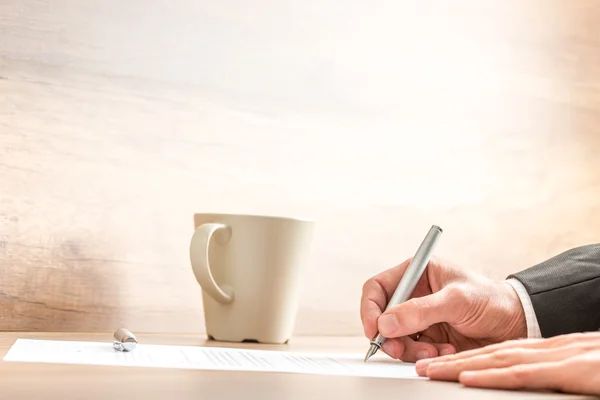 Empresario escribiendo con un bolígrafo en una hoja de papel — Foto de Stock