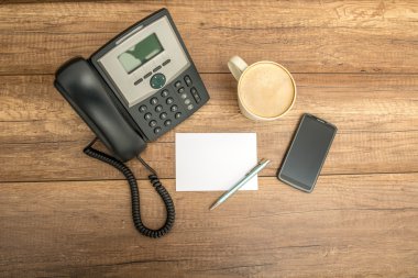 Top view of phone, blank paper, pen, coffee and a smart phone