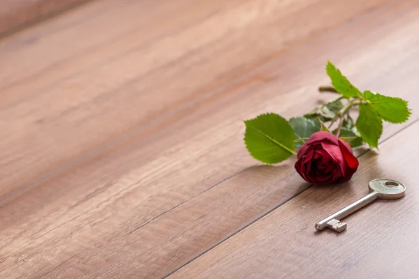 Long Stemmed Red Rose and Key on Wooden Surface — Stock Photo, Image