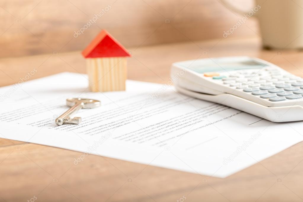 Silver house key lying on a contract for house sale