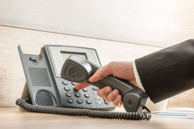Closeup of a hand in a formal elegant suit dialing a telephone n clipart