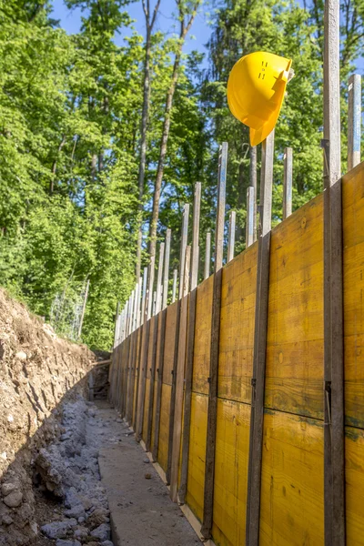 Conceito de canteiro de obras com um chapéu duro amarelo brilhante — Fotografia de Stock