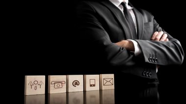 Businessman standing beside wooden blocks with drawings of commu