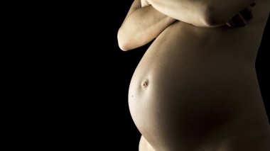 Closeup of a bare pregnant belly in a late stage of pregnancy