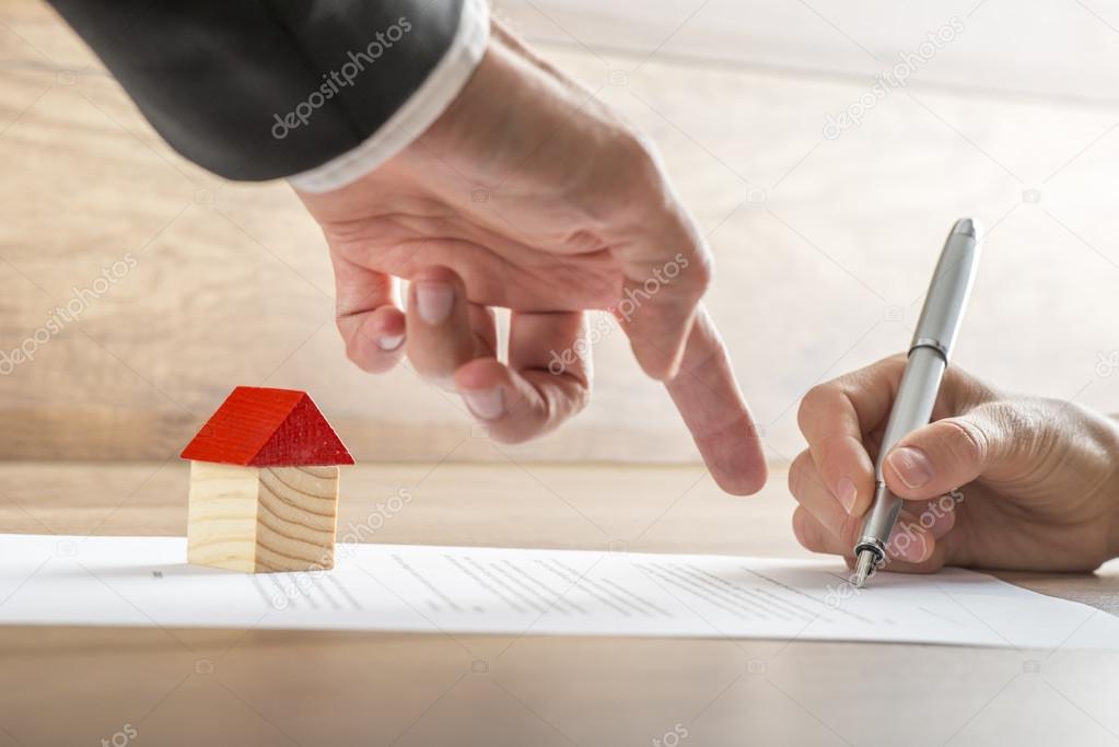 Real estate agent showing his client where to sign a contract of