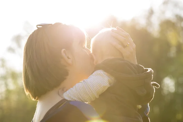 Młoda matka czule podnoszenia i całując jej Baby Boy — Zdjęcie stockowe