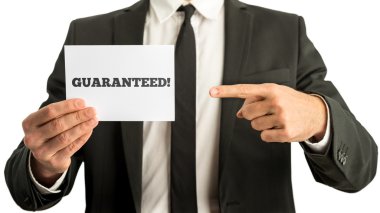 Closuep of businessman pointing to a white card with a Guarantee