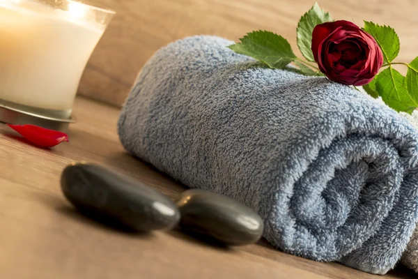 Luxurious wellness arrangement with a rolled blue towel, red ros — Stock Photo, Image