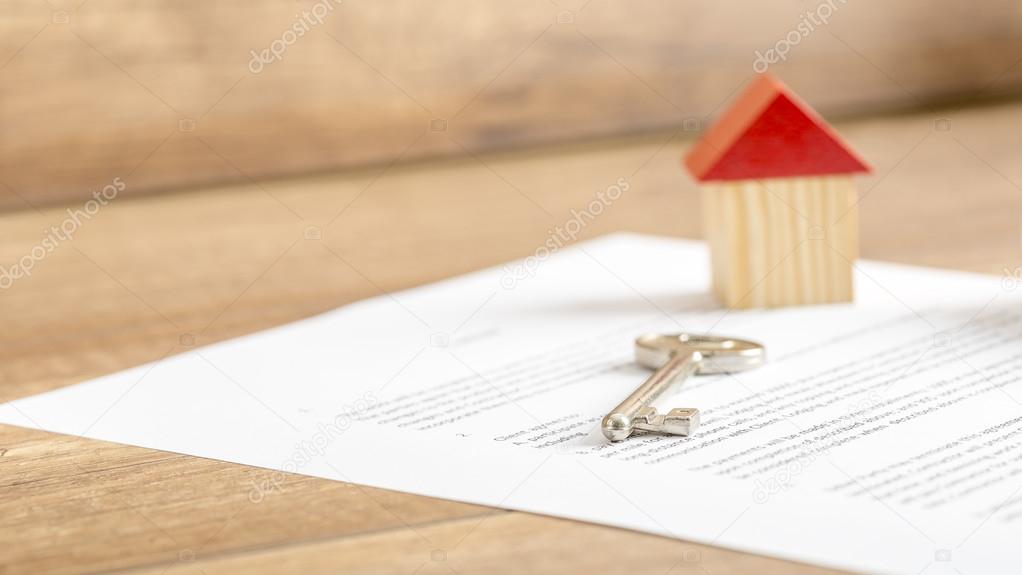 Silver house key lying on a contract of house sale