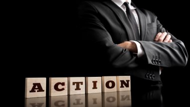 Businessman in a strong confident pose standing next to six wood