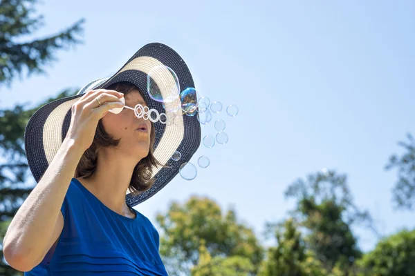 Young woman on summer holidays blowing soap bubbles — Stock Photo, Image