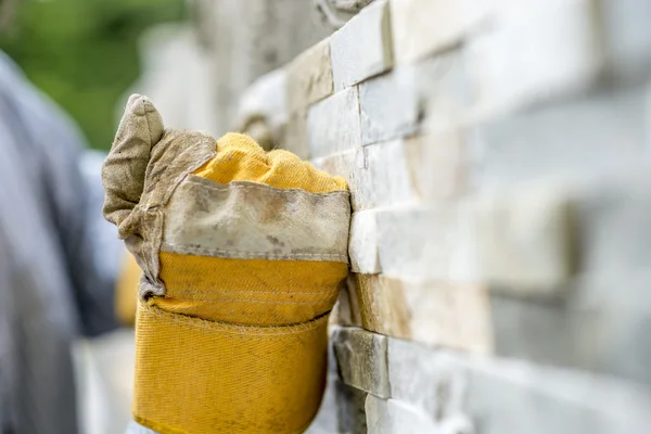 Fechar-se de trabalhador manual em luvas de proteção telha uma parede sagacidade — Fotografia de Stock