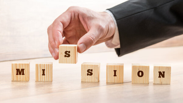 Closeup of businessman creating a word Mission with seven wooden