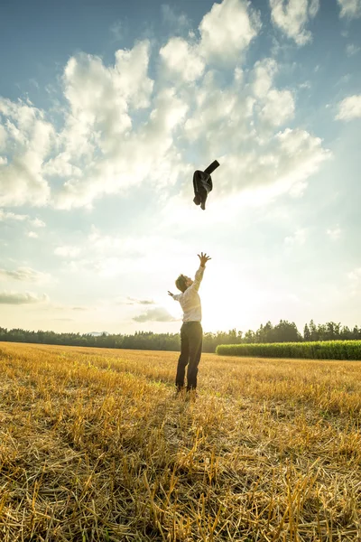 Бизнесмен бросает пальто в воздух на поле — стоковое фото