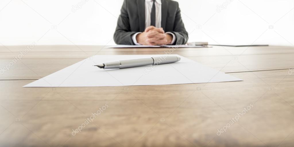 Businessman sitting at his wooden office desk with contract infr