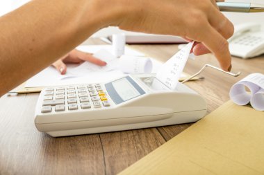Bookkeeper doing calculations on an adding machine clipart