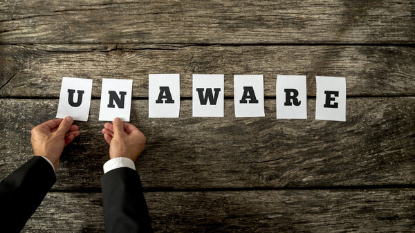 Top view of male hands taking away letters UN from the word unaw