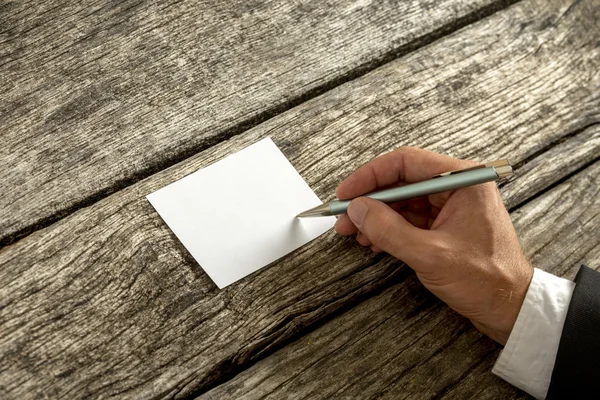 Vue aérienne d'une main en costume élégant écrivant sur blanc c — Photo