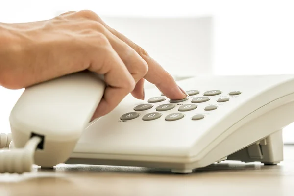 Closeup view of female secretary dialing a telephone number on w — 图库照片