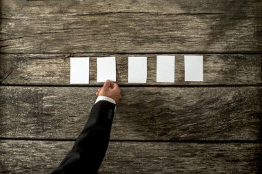 Top view of businessman hand placing five blank white peaces of 